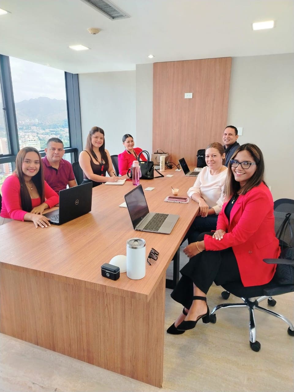 Sala Admin ejecutiva con 8 personas alrededor de mesa de madera y vista panorámica al valle